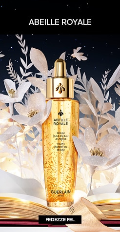 Guerlain Abeille Royale arany szérum üvegben, papírvirág dekorációval és csillagos háttérrel.